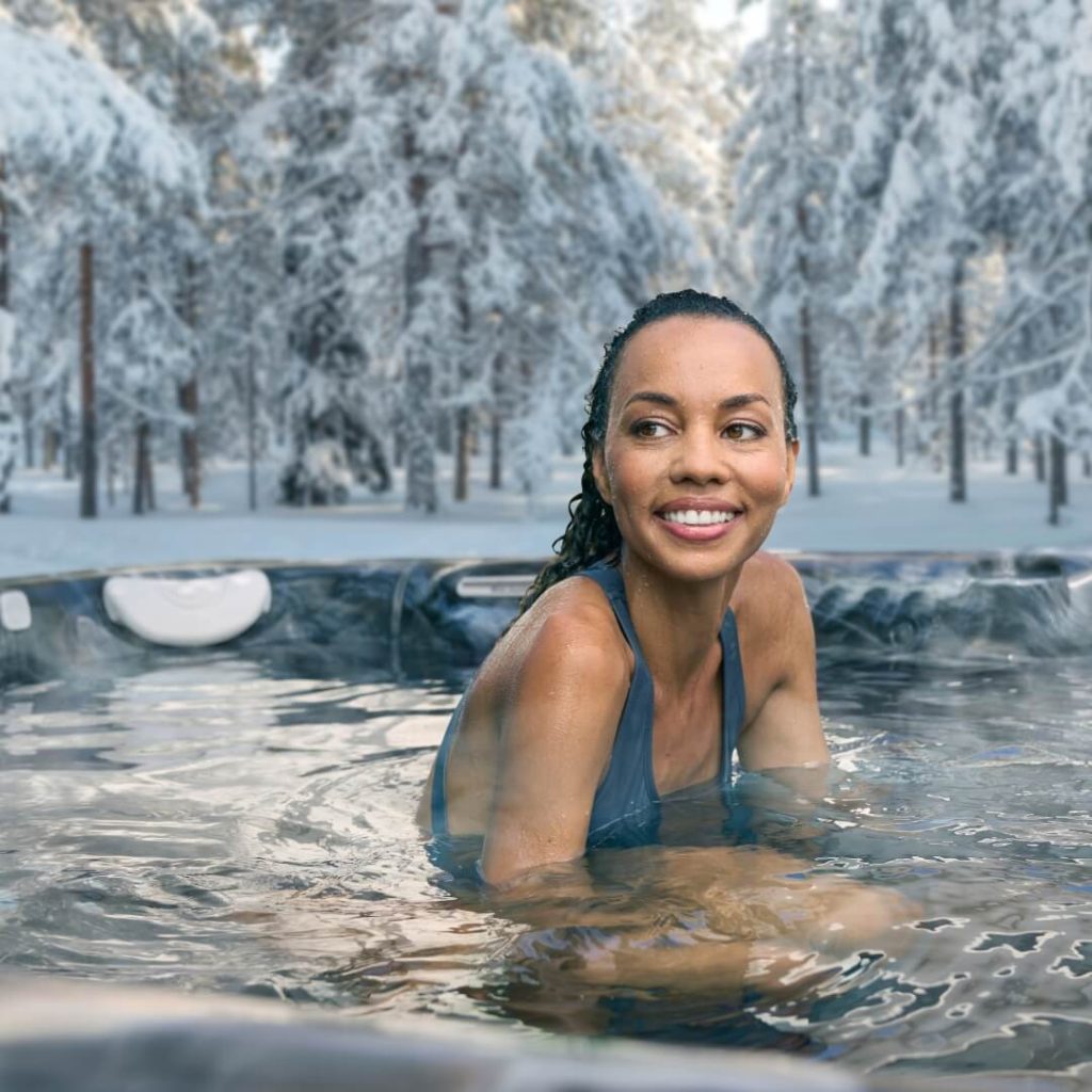 Woman happy in a hot tub spa at home in winter
