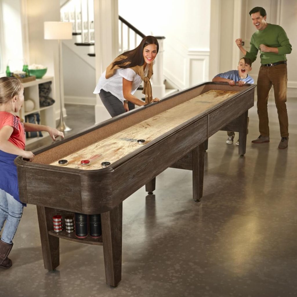 Family with children playing on a shuffleboard in a game room